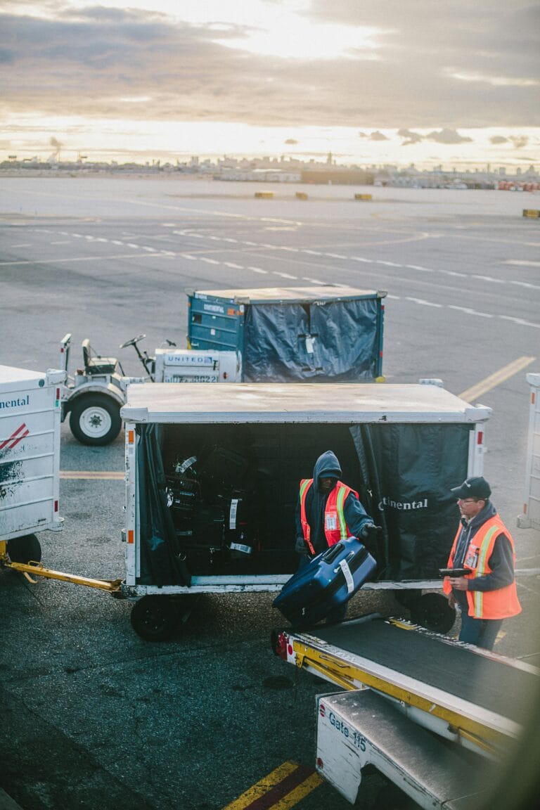 Baggage handlers loading and unloading suitcases from an airport conveyor belt