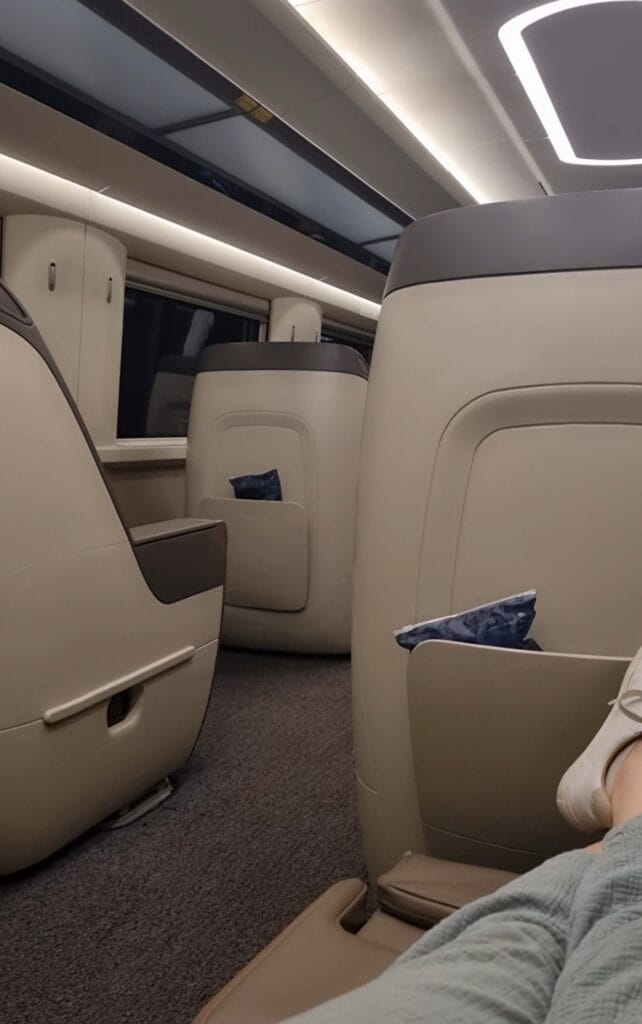 Luxurious business class seats on China high-speed train, featuring spacious leather armchairs that recline fully flat, with personal entertainment screens and ample privacy