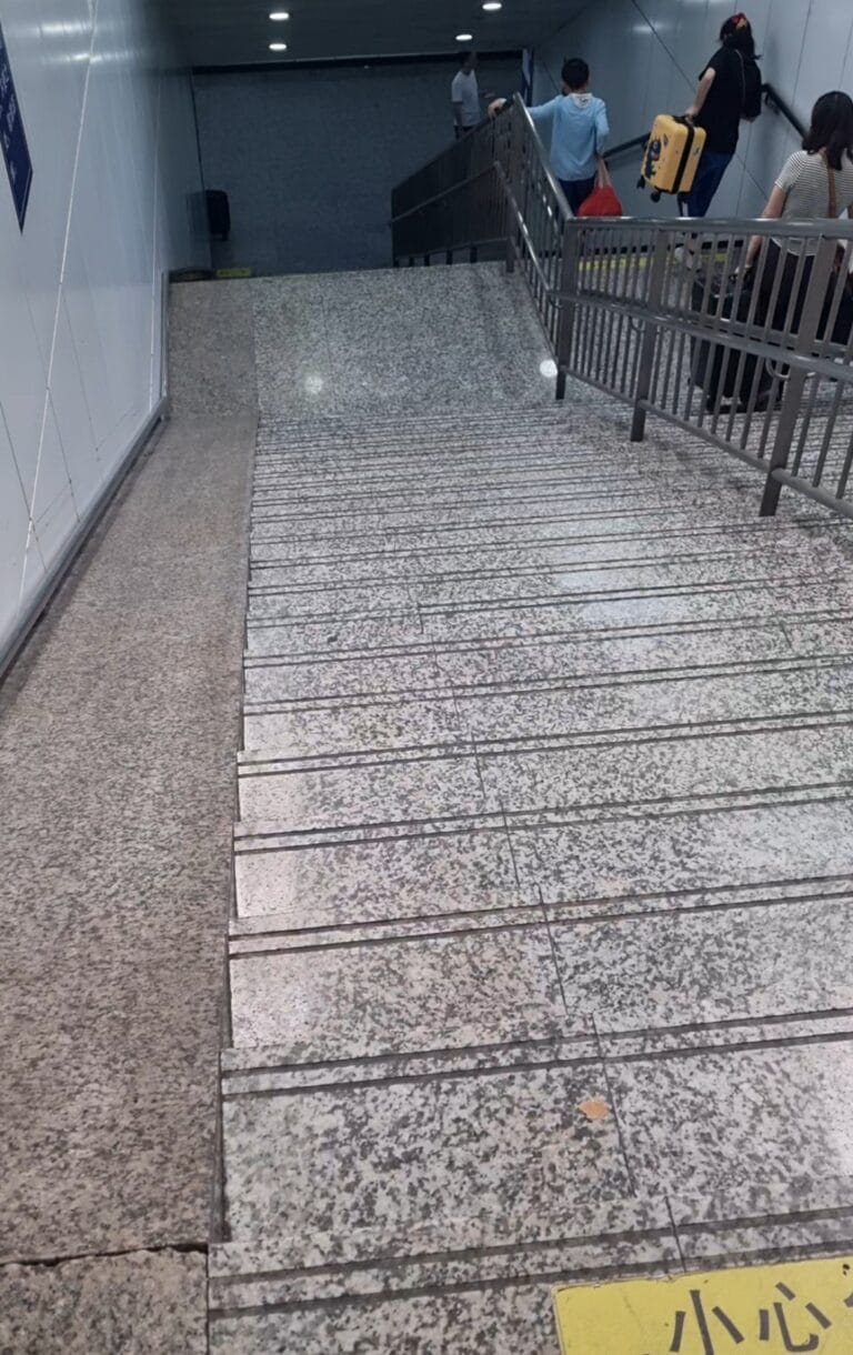 Large staircase at Chinese train station with no elevator or escalator, travelers are required to carry heavy luggage down a long flight of steps