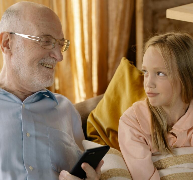 Grandpa smiling and talking with young granddaughter symbolizing warm, supportive father figure guidance.