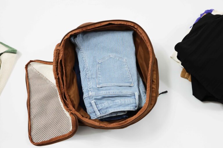 Hand loading folded jeans into the bottom of a compression packing cube