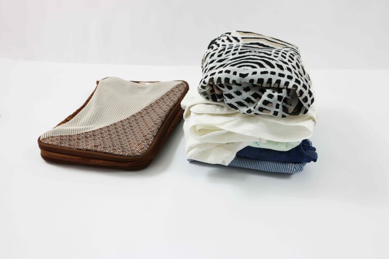 Pile of folded clothes next to an empty compression packing cube